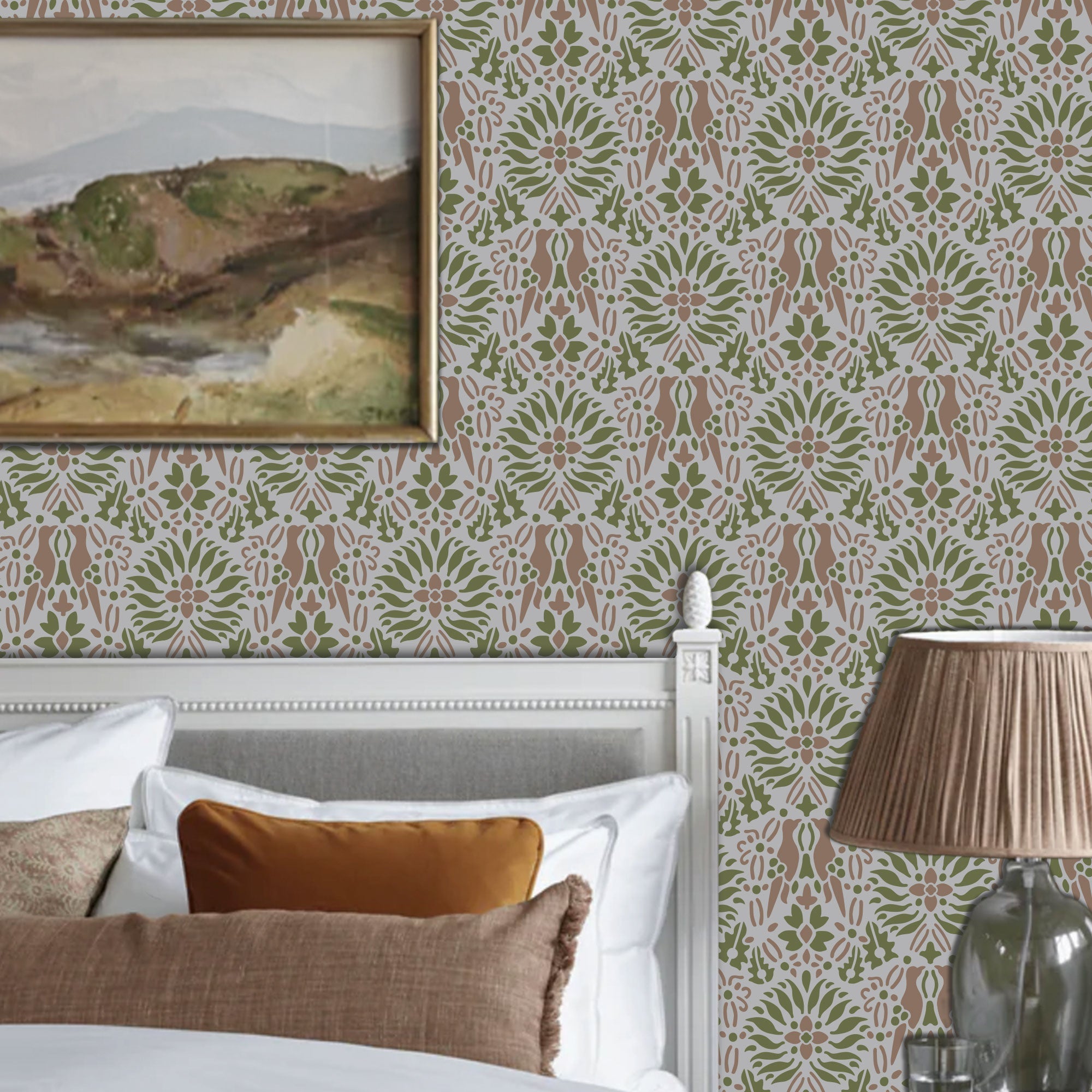 Morning dove stencil applied in a  bedroom corner, a white wooden bed frame, with a framed landscape painting on the wall and a pleated beige lamp on a glass table, and light highlighting the green, mauve and grey painted stencil on the wall.