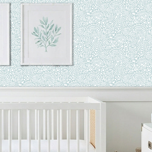 Abstract Seashells wall stencil applied behind a white crib and natural light highlighting the bluish green and white painted stencil on the wall.
