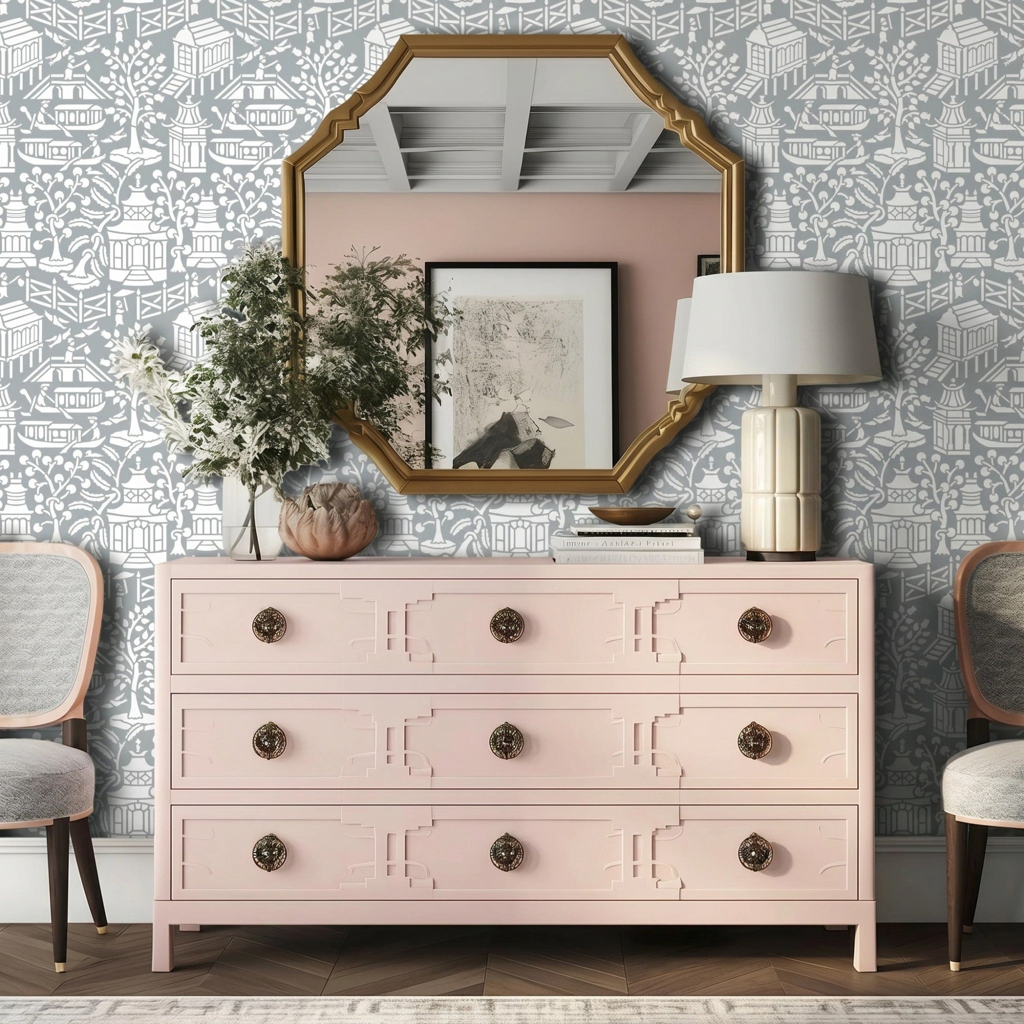Asian garden wall stencil applied in a styled interior corner featuring a pink dresser, a white table lamp with a ribbed cream base, a gold-framed mirror, two chairs, and natural light highlighting the gray and white painted stencil on the wall.
