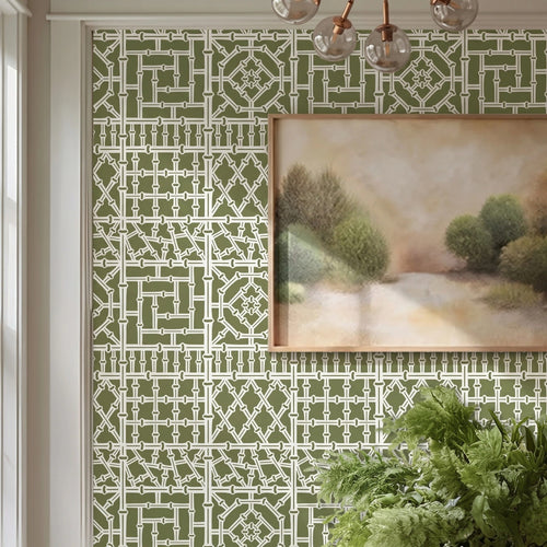 Bamboo wall stencil in a dining room, styled with a framed landscape painting and a green plant, and natural light highlighting the green and white painted stencil on the wall.