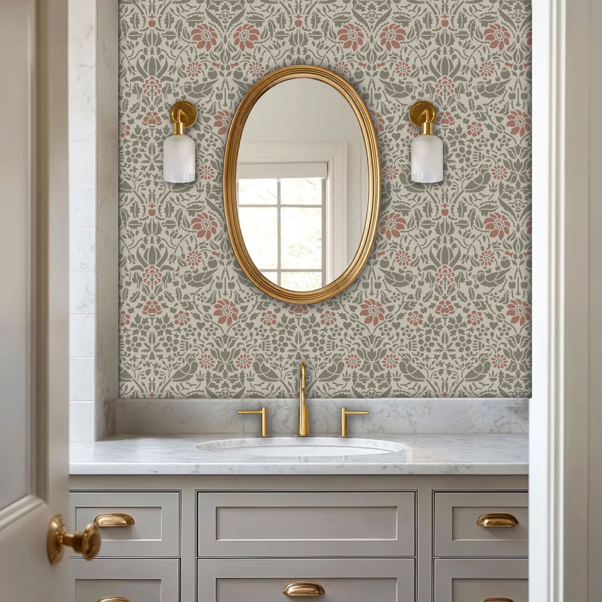 Birds and berries wall stencil applied in a powder room with an oval mirror with a gold frame featuring a repeating pattern of birds, flowers, and leaves in muted green and pink tones painted stencil on the wall.
