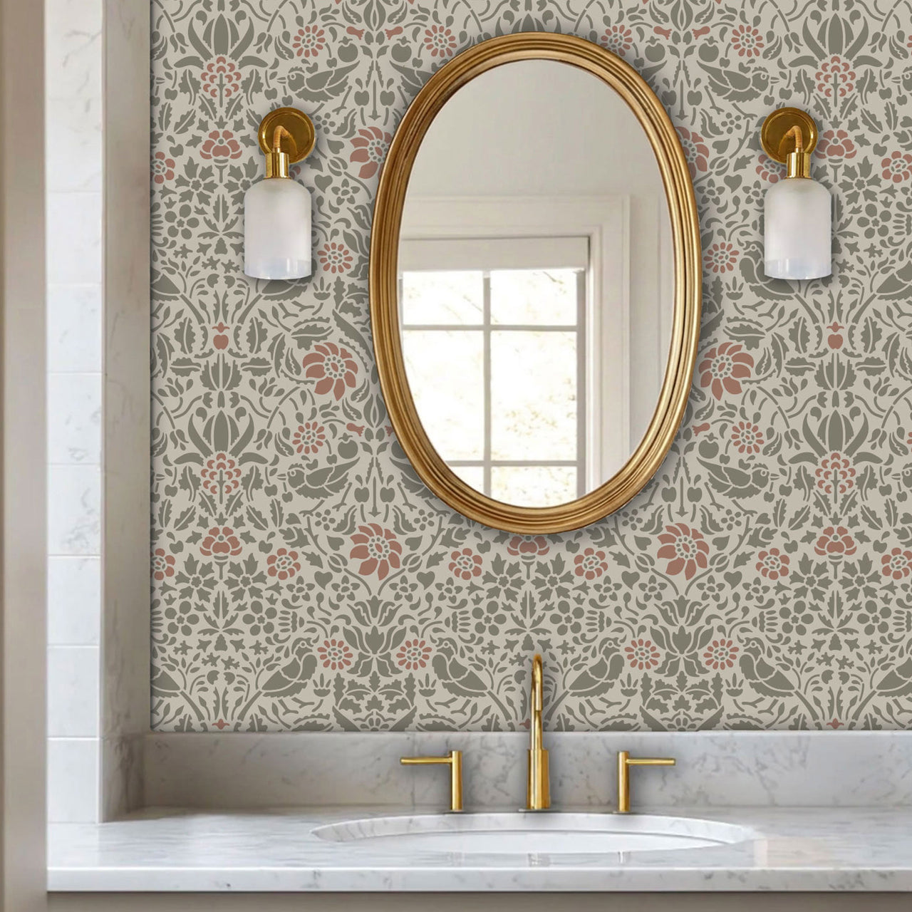 Birds and berries wall stencil applied in a powder room with an oval mirror with a gold frame featuring a repeating pattern of birds, flowers, and leaves in muted green and pink tones painted stencil on the wall.