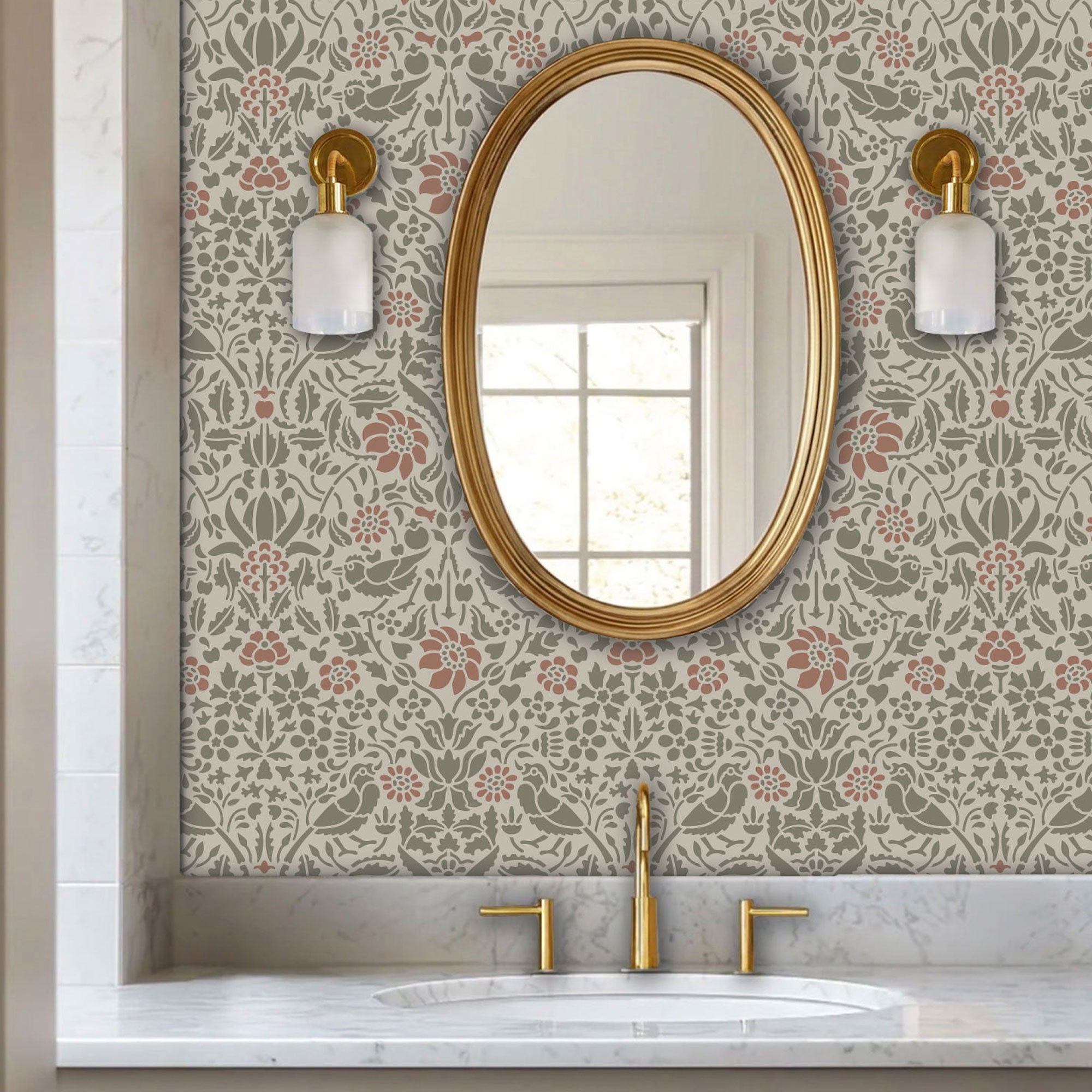 Birds and berries wall stencil applied in a powder room with an oval mirror with a gold frame featuring a repeating pattern of birds, flowers, and leaves in muted green and pink tones painted stencil on the wall.