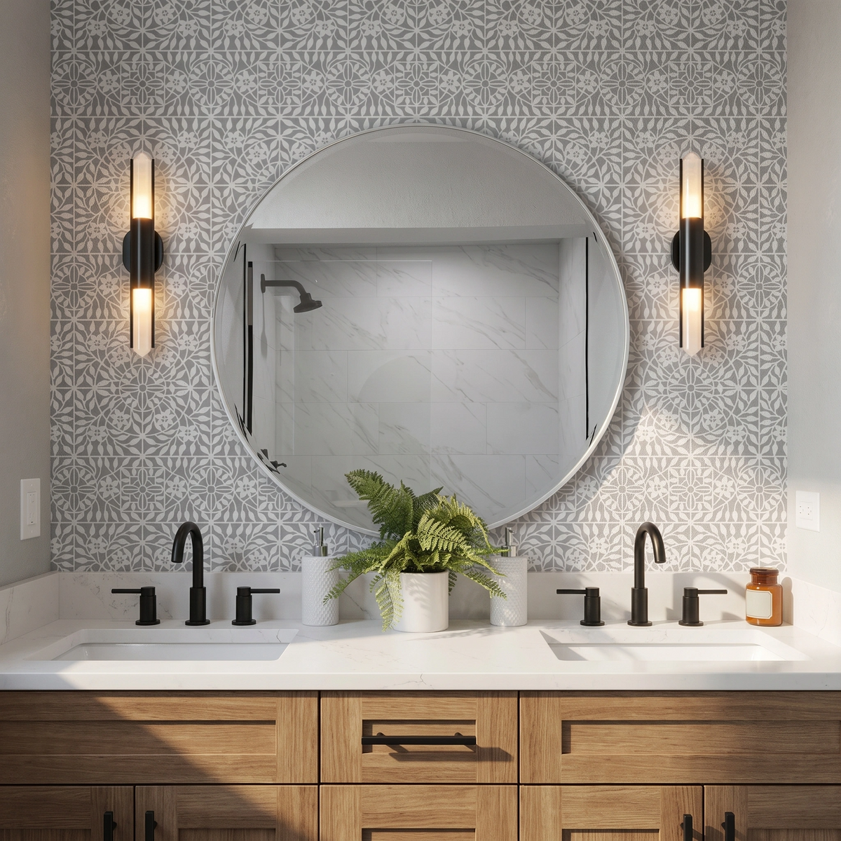 A modern wall-mounted sconce with a black metal frame and two vertical frosted glass lights emitting warm light, mounted on the wall painted with botanical tile wall stencil in grey next to a large round mirror.