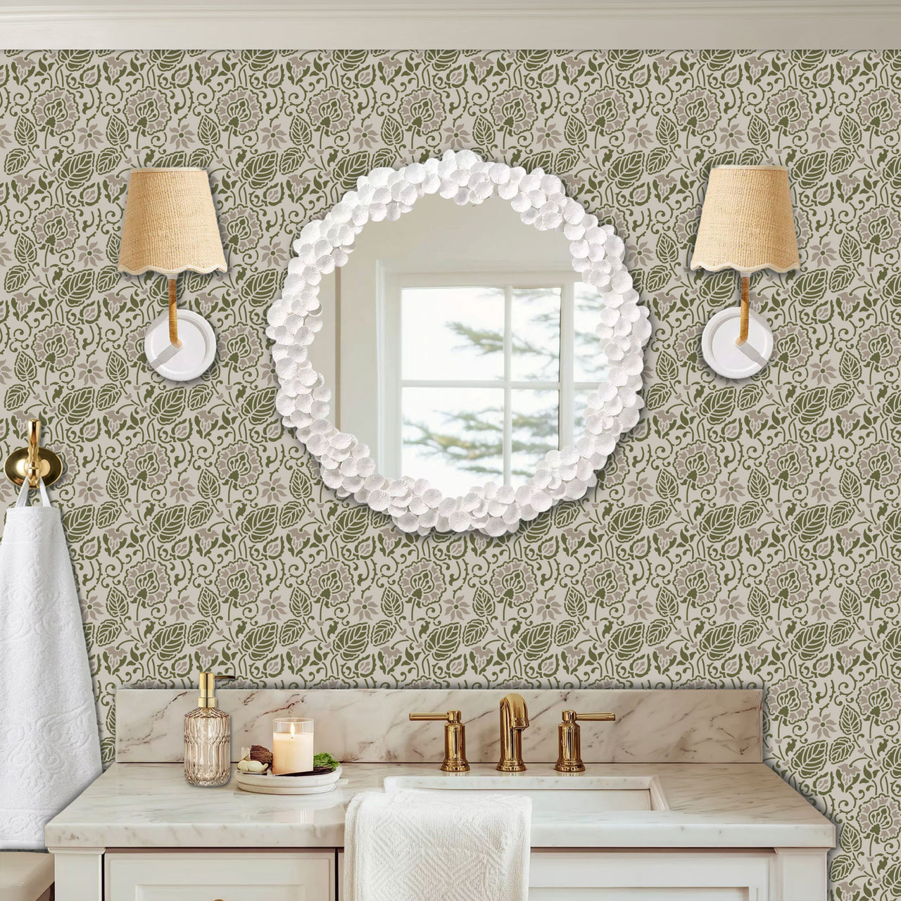 Dandelion wall stencil in a powder room with a round wall mirror, with wall sconces, and a marble sink with brass fixtures, with natural light highlighting the olive green and soft taupe painted stencil on the wall.