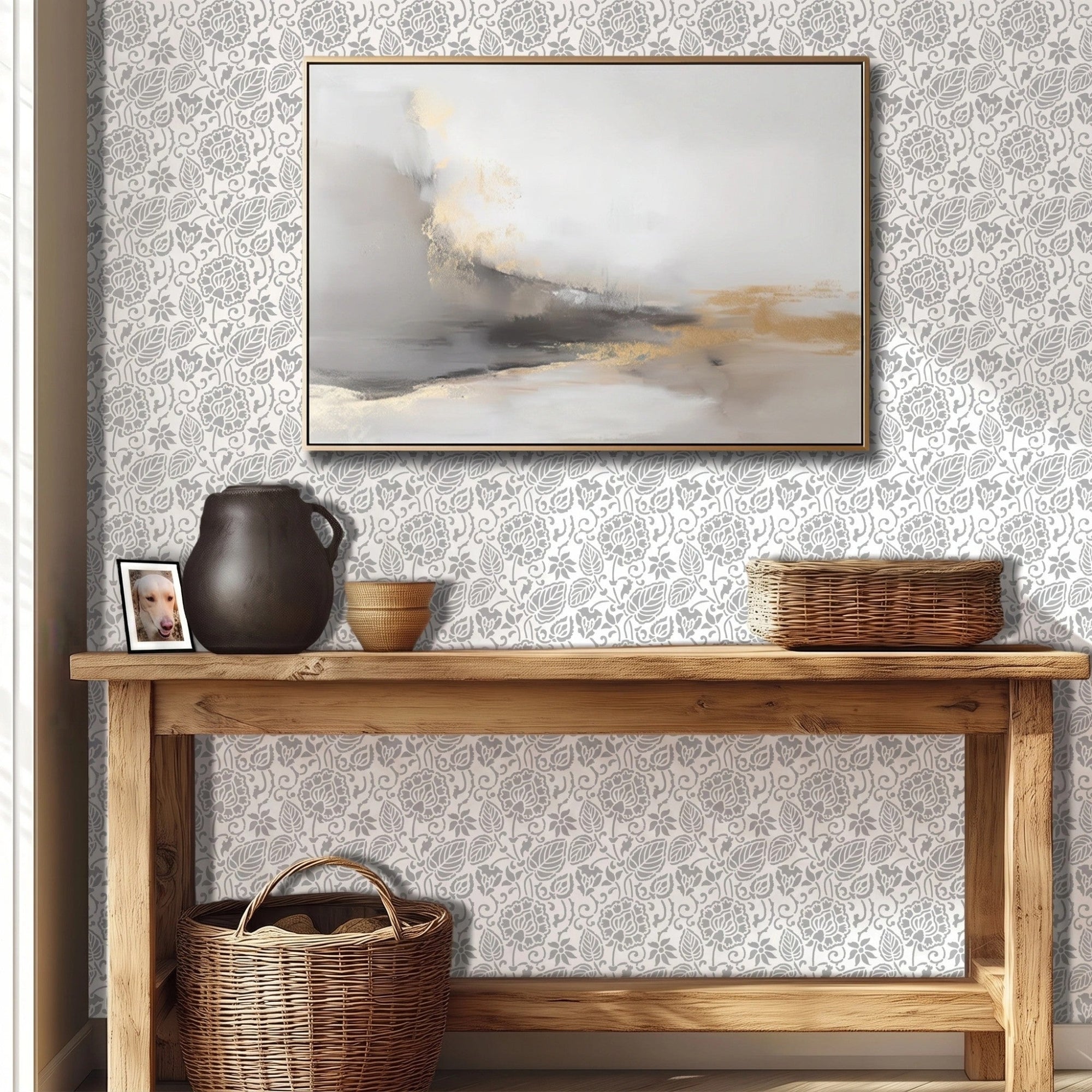 Dandelion wall stencil featured in a hallway with a wooden console table, a dark ceramic pitcher, a small woven bowl, and a framed abstract painting on the wall, with natural light highlighting the gray and white stencil painted on the wall.