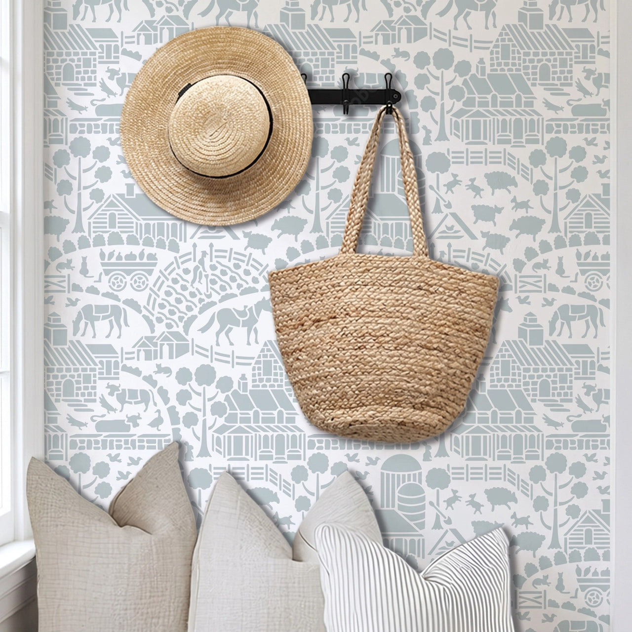 Day at the farm farmhouse wall stencil applied in a mudroom with pillows, a hat and basket hanging on the wall, and natural light highlighting the light blue and white painted stencil on the wall.