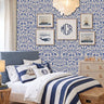 Dogs in the garden wall stencil applied in a children's bedroom featuring a bed with navy and white striped bedding, framed prints, a wood dresser, and a chandelier, and natural light highlighting the dark blue and beige painted stencil on the wall.