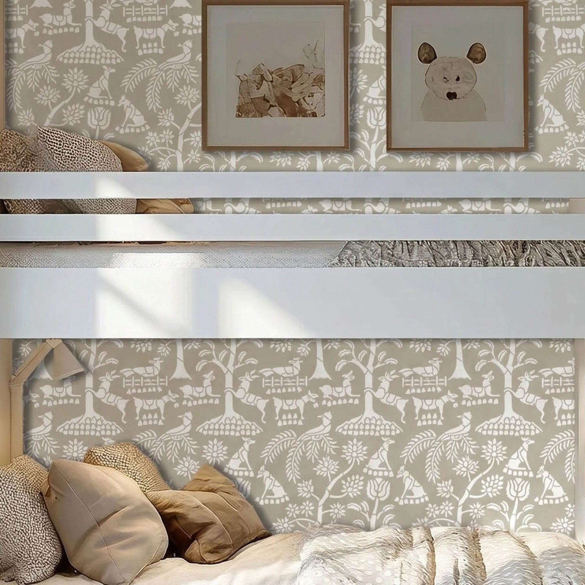Enchanted forest wall stencil in a children's bedroom featuring a white bunk bed, two framed animal prints on the wall, bedding and pillows, with natural light highlighting the taupe and white painted stencil on the wall.