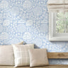 Floral Garden wall stencil applied in a bright room with a wooden bench and a window, and natural light highlighting the light blue and white painted stencil on the wall.