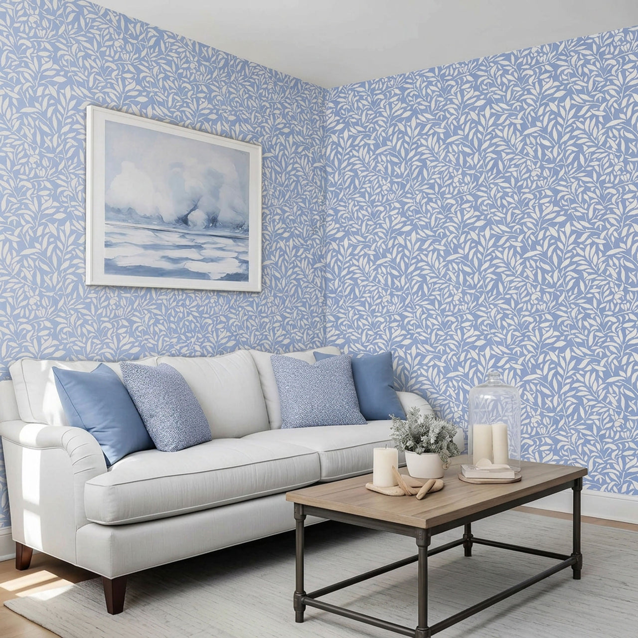 Hummingbird stencil on a wall above a sofa with blue and textured pillows, with a framed landscape print hanging on the wall, natural soft light highlighting the blue and white painted stencil on the wall.
