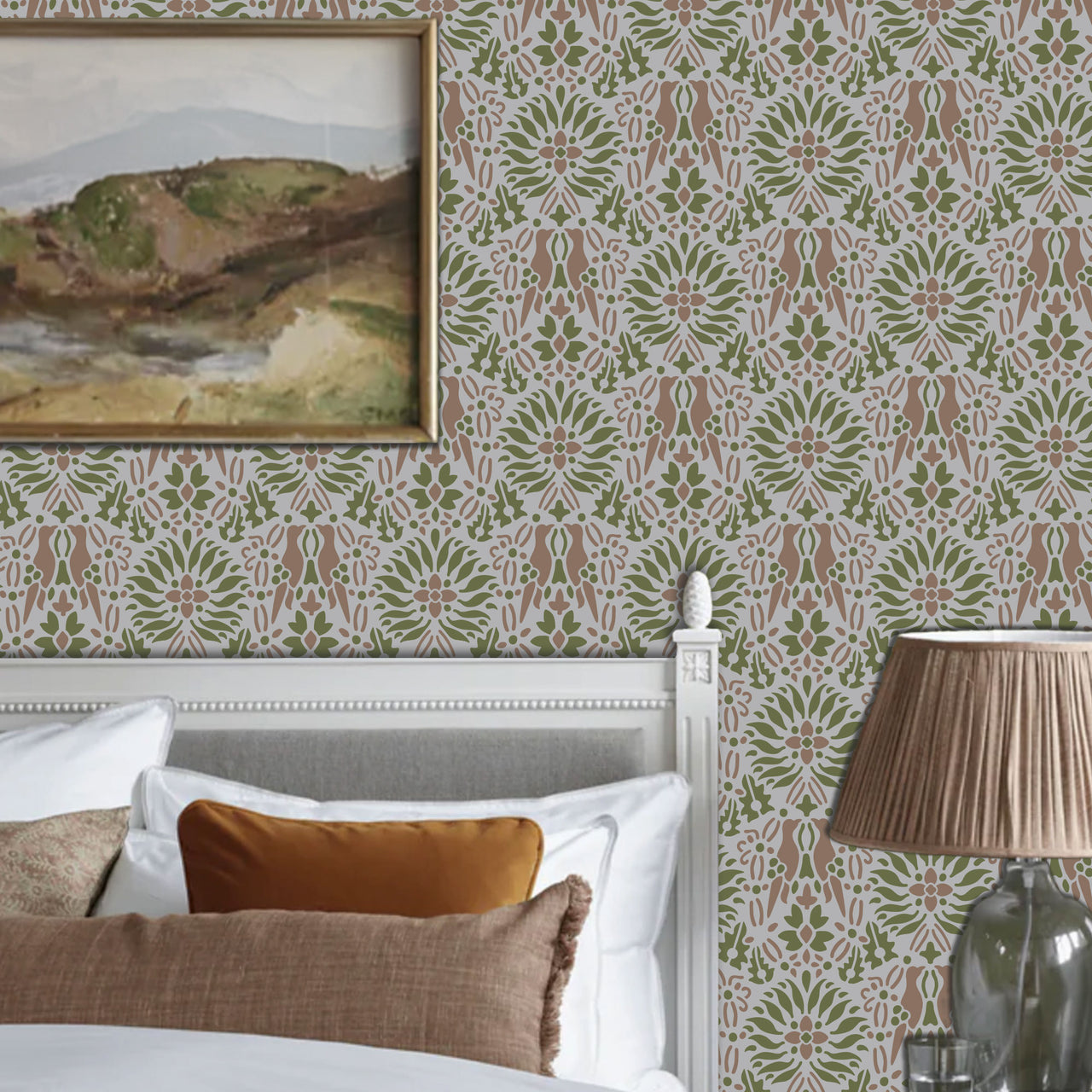 Morning dove stencil applied in a  bedroom corner, a white wooden bed frame, with a framed landscape painting on the wall and a pleated beige lamp on a glass table, and light highlighting the green, mauve and grey painted stencil on the wall.
