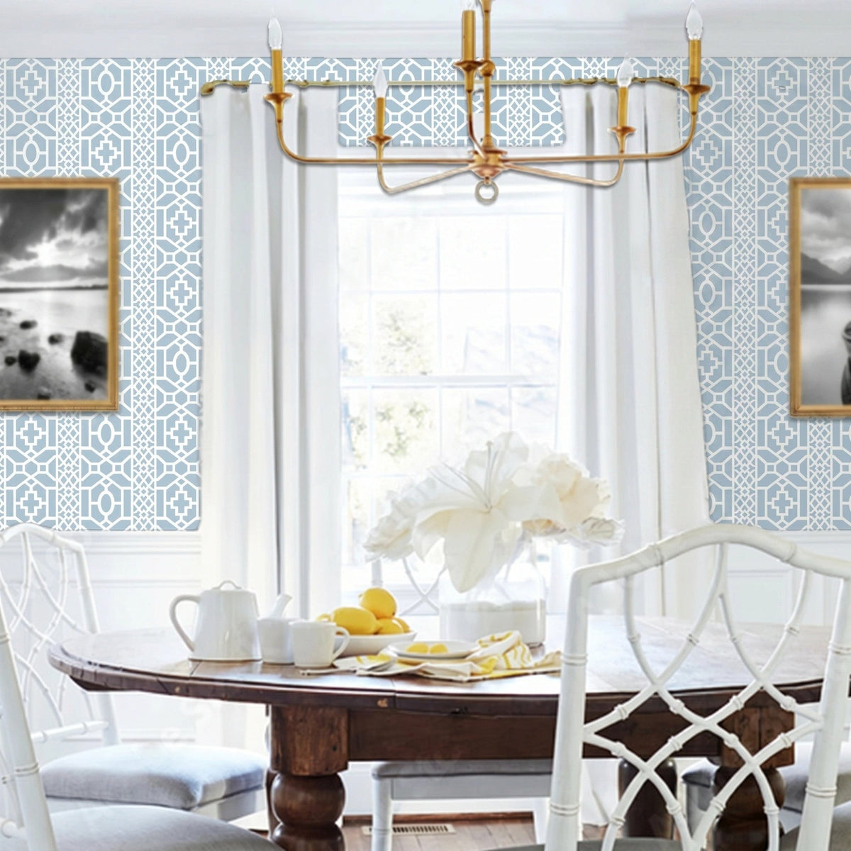 Moroccan Lattice wall stencil applied in a dining room featuring a round wooden table with white chairs, a gold chandelier, a window with curtains, and natural light highlighting the light blue and white geometric stencil on the wall.