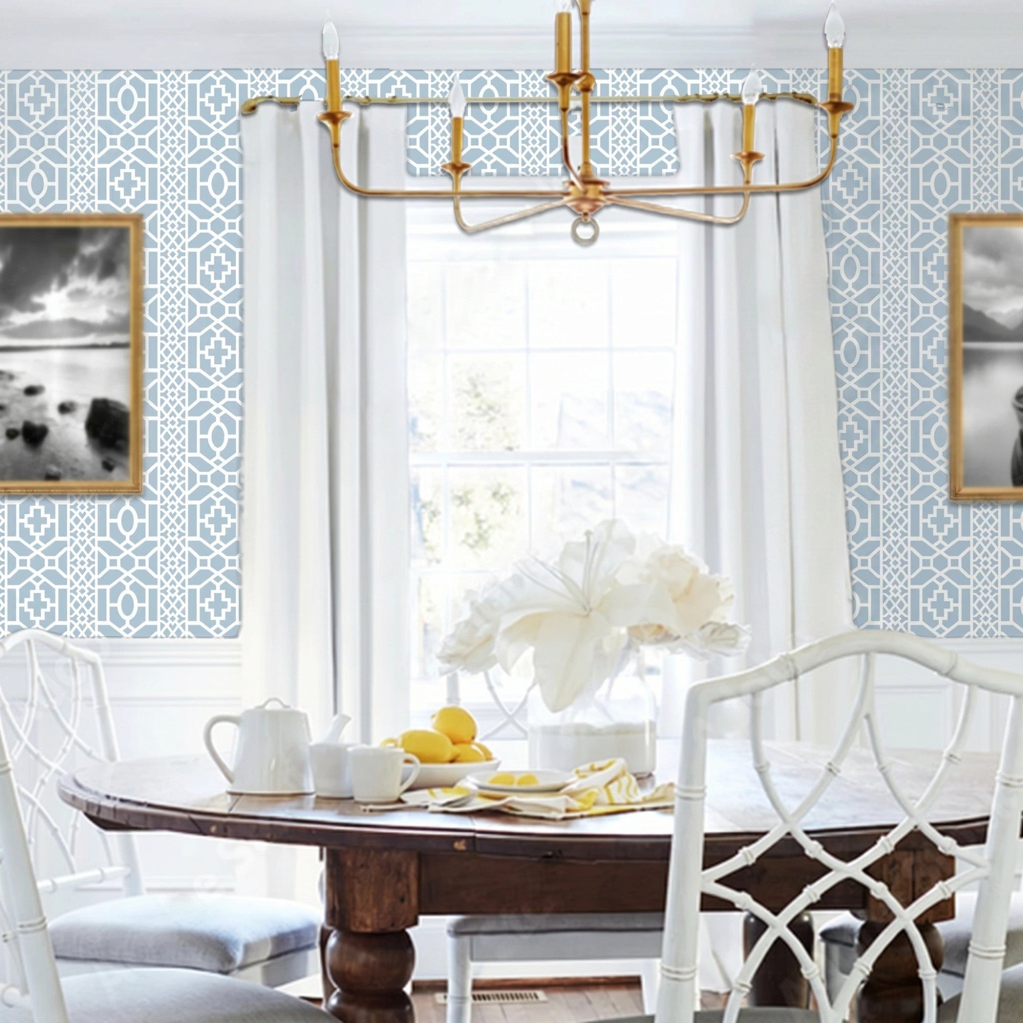 Moroccan Lattice wall stencil applied in a dining room featuring a round wooden table with white chairs, a gold chandelier, a window with curtains, and natural light highlighting the light blue and white geometric stencil on the wall.