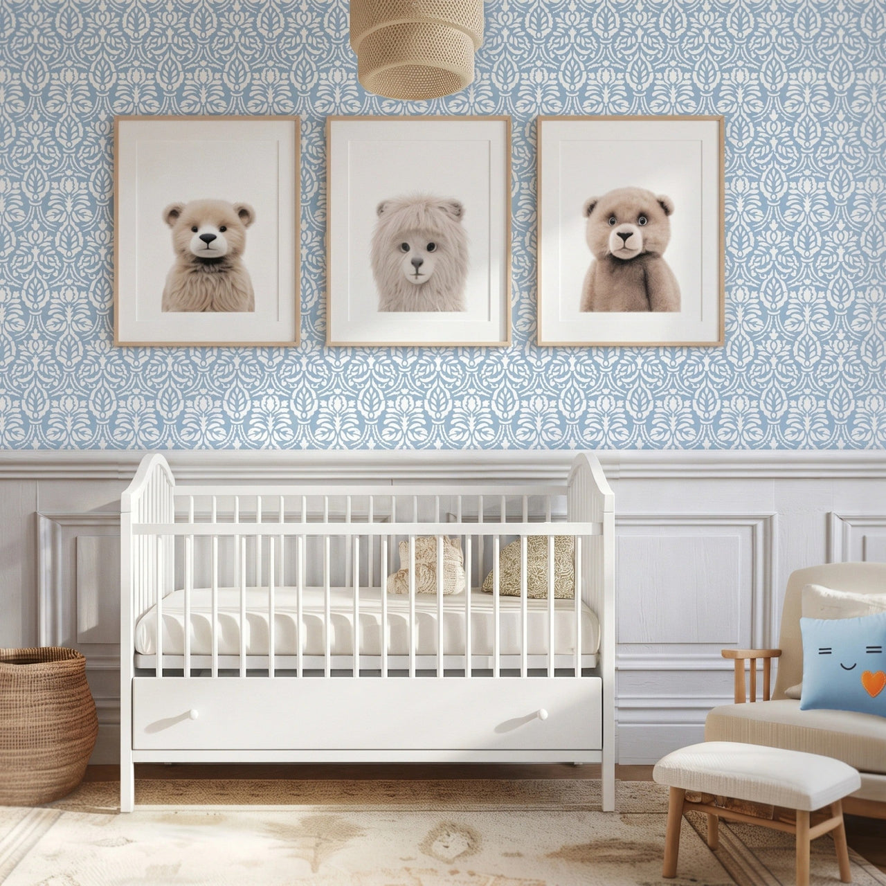 Spear thistle wall stencil in a styled nursery wall featuring, three framed art prints of teddy bears, and a white wooden crib at the bottom, and natural light highlighting the blue and white floral painted stencil on the wall.