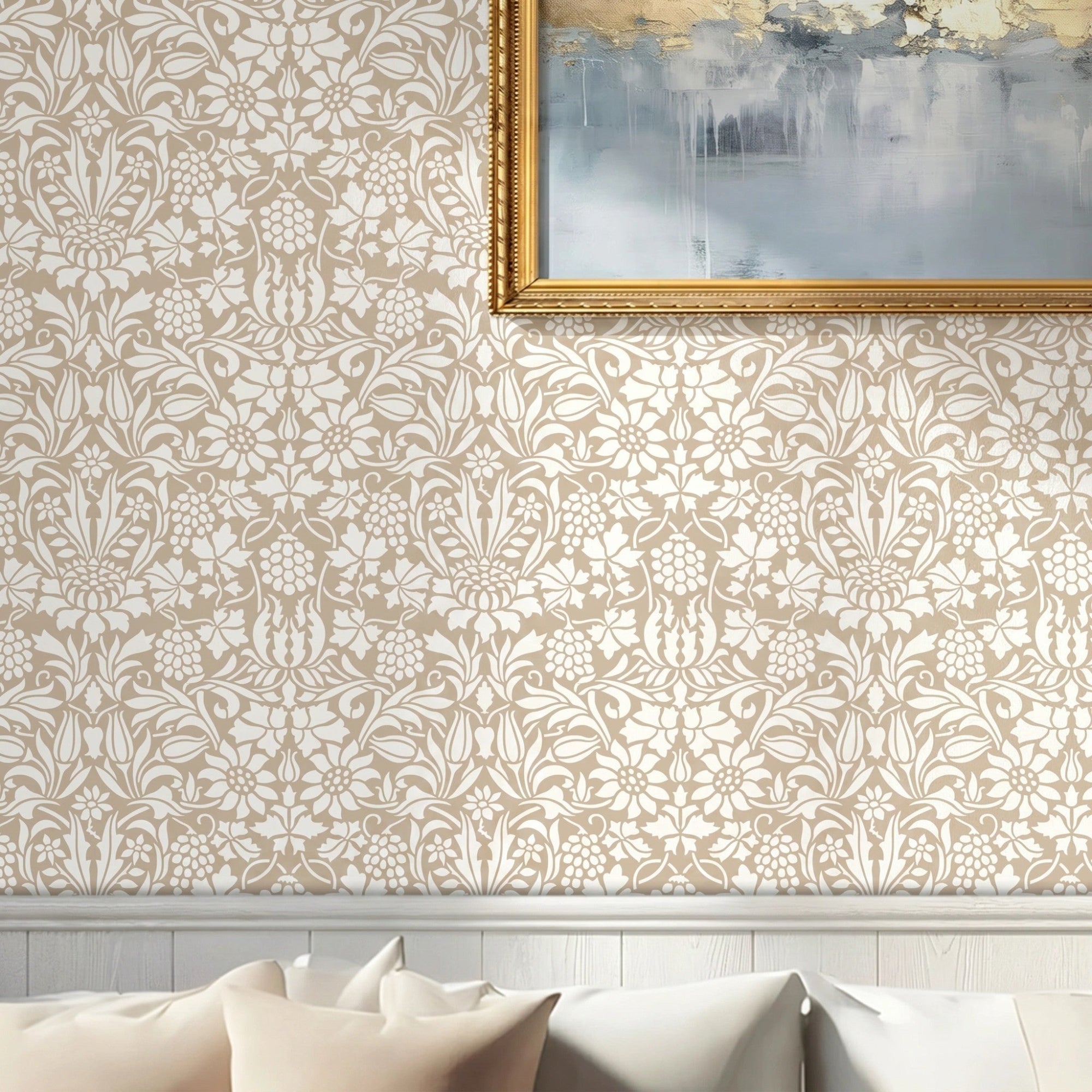 Thistle and Vine wall stencil pattern applied in a living room setting with beige pillows, chair rail molding and a painting with a gold frame, and natural light highlighting the beige and cream painted stencil on the wall.