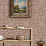 Topiary garden wall stencil applied in a hallway featuring a framed landscape painting hanging above a wooden table holding books and decorative objects, and soft light highlighting the dusty rose and beige painted stencil on the wall.