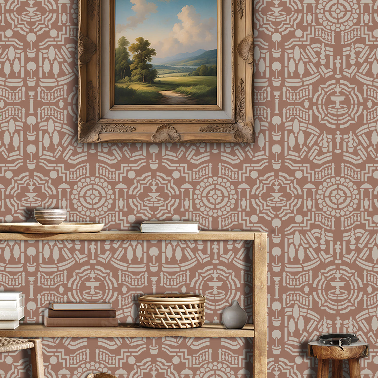 Topiary garden wall stencil applied in a hallway featuring a framed landscape painting hanging above a wooden table holding books and decorative objects, and soft light highlighting the dusty rose and beige painted stencil on the wall.
