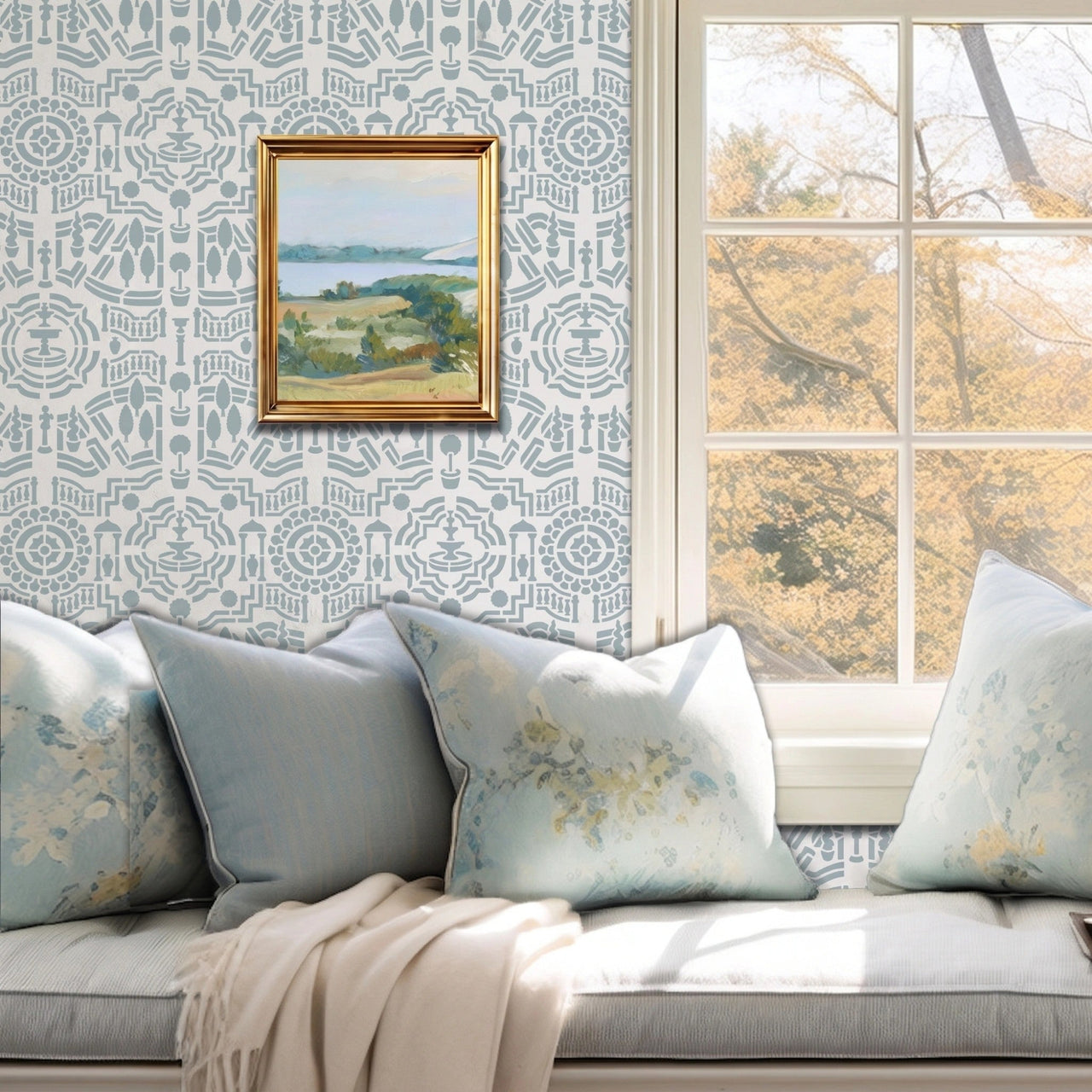 Topiary Garden wall stencil featuring a window seat cushion, a landscape paintings on the wall, and a window with natural light highlighting the light blue and dark blue painted stencil on the wall.