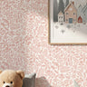 Woodland Foxes wall stencil applied in a soft pink and white nursery, shown behind a framed woodland village print with a teddy bear and pillows below, and the soft pink and white painted stencil on the wall.