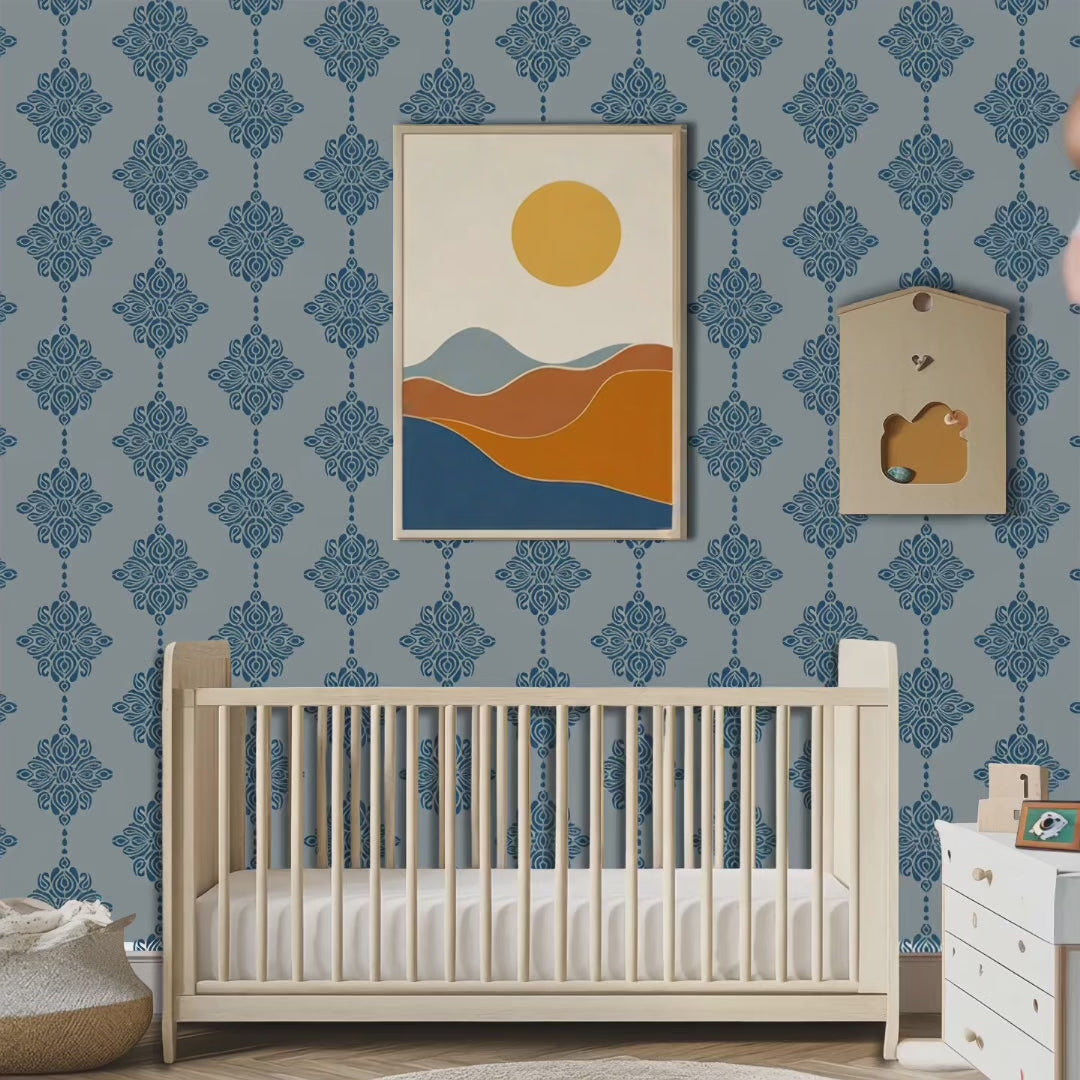 Video of damask block print stencil applied in a nursery, styled with a minimalist framed art print of rolling hills and a sun, and the top of a light wood crib, with natural light highlighting the dark blue on light blue stencil painted on the wall. Man walks in carrying a baby followed by a dog. Man places baby in the crib, exits the room and the dog stays.