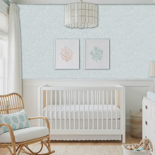 Video of abstract seashells wall stencil applied behind a white crib and natural light highlighting the bluish green and white painted stencil on the wall. Pregnant woman walks into nursery followed by a dog, touches the wall stencil in admiration, pets the dog and they leave the room.
