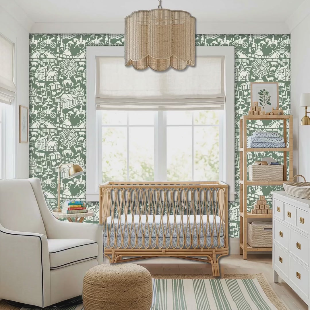 Video of english storybook wall stencil applied in a nursery featuring a crib, a chair, a hanging light and a window, white chest of drawers and natural highlighting the dark green and white painted stencil on the wall. Woman gets out of the chair, places the bay in the crib and exits the room.
